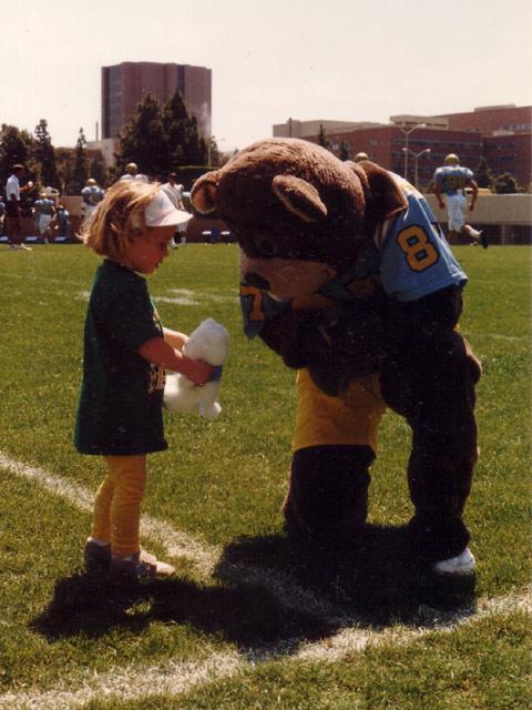 Joe Bruin with a young child before a football game