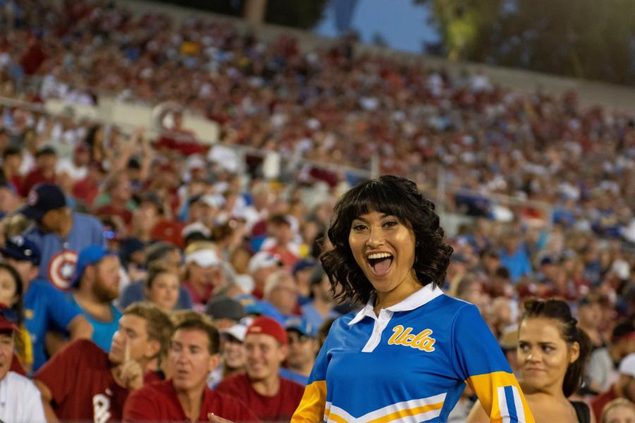 Member of the UCLA Yell Crew wearing her blue uniform, posing in the stands at the Rose Bowl during the UCLA / Oklahoma football game.