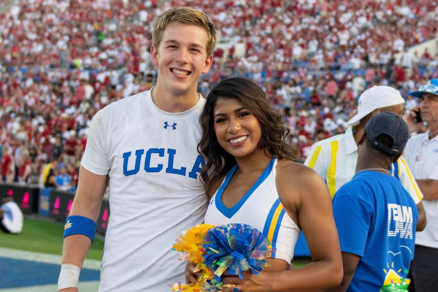 Two members of the UCLA Cheer Squad, standing together in uniform on the field at the Rose Bowl during the UCLA / Oklahoma football game.